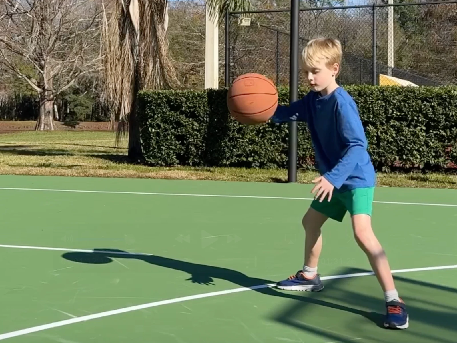 A child dribbling a basketball on an outdoor court